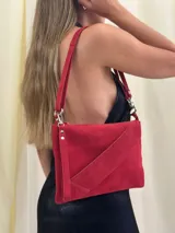 Sobre/cartera de gamuza color marrón oscuro, con diseño de solapa diagonal. Incluye una correa larga para usar al hombro o como bandolera, y una correa corta para la muñeca, ambas desmontables.
