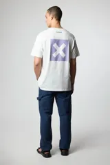 Remera blanca de algodón con cuello redondo y manga corta. Estampado en el pecho con un cuadrado lila y una "X" en el centro.