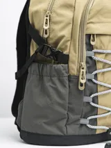 Mochila gris claro y gris oscuro con cordones elásticos cruzados en el frente y logo de la marca en la parte superior.