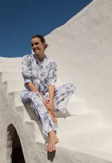 Camisa blanca con estampado floral azul, de lino, con cuello mao, mangas abullonadas al codo y cierre frontal con botones de madera.