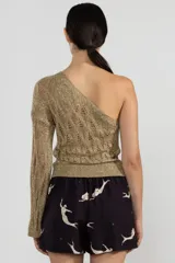 Top dorado de tejido calado, con un solo hombro y manga larga acampanada.