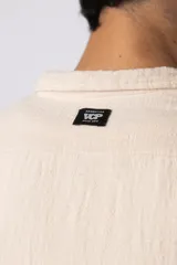 Camisa de lino blanca de manga larga, con cuello clásico y cierre frontal con botones. Corte recto y holgado.