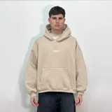 Buzo hoodie color beige, corte oversize, con bolsillo tipo canguro y bordado frontal con la palabra 'VENEVO'.