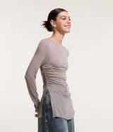 Blusa de viscosa color gris con efecto gastado, cuello redondo, mangas largas, fruncido lateral y abertura.