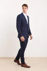 Traje de vestir azul marino, compuesto por saco de dos botones y pantalón de corte slim. Incluye camisa blanca de vestir y zapatos marrones acordonados.
