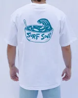 Remera blanca de algodón con cuello redondo y estampado en el pecho con el texto "Denali Surf Co." y una tabla de surf.