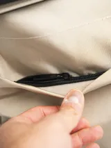 Mochila color beige con cierre superior enrollable y hebilla de ajuste.