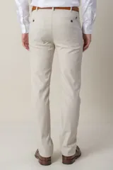 Pantalón de vestir color beige, de corte clásico, con bolsillos laterales y traseros. Se ajusta a la cintura con cinturón de cuero marrón.