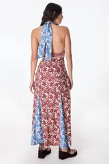 Vestido midi con estampado floral en tonos azul, rojo y beige. Tiene cuello halter con abertura en el pecho y falda con abertura lateral.