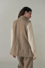 Chaleco color beige, entallado, con solapa, bolsillos plaqué y terminaciones envivadas.