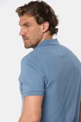 Remera polo azul de piqué liso, con cuello de rib y botones personalizados.