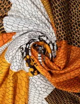 Pashmina cuadrada de satén estampado en tonos naranja, blanco y negro, con diseño de escamas.