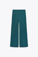 Pantalón marrón de tiro alto con trabillas, doble pliegue, bolsillos laterales y de vivo en la espalda, pernera ancha y cierre frontal con cremallera y gancho metálico.