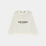 Sweater de punto grueso color blanco hueso, con cuello redondo, corte cuadrado y ligeramente corto. Presenta un gráfico frontal con el texto "EME STUDIOS curated by ben ice" en color marrón. Tiene puños ajustados.