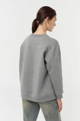 Buzo de frisa de algodón gris, de calce oversize con escote redondo y estampa tipográfica en el frente.