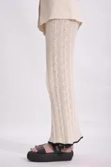 Pantalón de punto color crema, de corte acampanado y cintura alta.