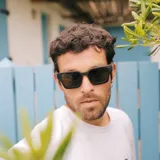 Lentes de sol con marco cuadrado de madera color marrón oscuro y lentes verdes.