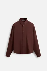 Camisa color borgoña de corte relajado, confeccionada en tejido con mezcla de viscosa. Tiene cuello solapa, manga larga con puños abotonados, bolsillo de parche en el pecho y cierre frontal con botones.