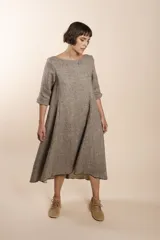 Vestido largo debajo de la rodilla, acampanado, color marrón, con cuello bote, bolsillos laterales y mangas 3/4 con detalle de tajo.