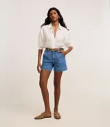 Short de jean azul de tiro alto con bolsillos delanteros y traseros, trabillas en la cintura y pespuntes en color contrastante.