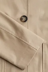 Campera color beige de corte holgado en sarga de algodón. Modelo con cuello, cierre de botones y bolsillos parche delanteros.
