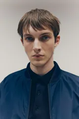 Campera bomber azul marino con cuello elevado acanalado y cierre frontal. Tiene bolsillos laterales y un bolsillo interior, todos con cierre. Los puños y el bajo son acanalados. Está forrada.