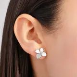 Aros plateados con forma de flor con pétalos blancos y centro brillante.