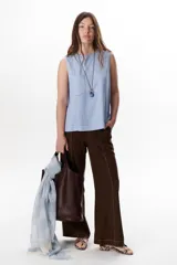 Top sin mangas color terracota con cuello redondo y bolsillo frontal. Presenta costuras a contratono en blanco que definen los bordes y el bolsillo.