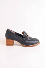 Mocasín de cuero color azul marino con aplique metálico dorado y taco de madera.
