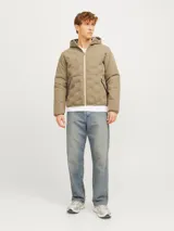 Campera híbrida color caqui, ligera e impermeable, con capucha, cierre frontal con cremallera, mangas largas con puños elásticos y bolsillos frontales con cierre.