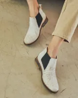 Botines Chelsea de cuero negro con elástico lateral y suela marrón.