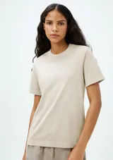 Remera color beige de corte clásico, con cuello redondo y mangas cortas.