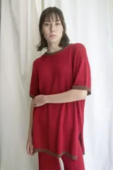 Remera roja de tejido artesanal en hilado 70% algodón y 30% acrílico, con cuello y mangas con ribete marrón. Corte holgado y aberturas laterales en el ruedo.