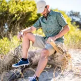 Short de hombre color verde oliva, con bolsillos laterales y traseros con cierre. Protección solar UPF 50 y repelencia al agua.