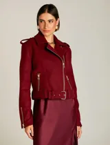 Chaqueta corta color borgoña, estilo motociclista, con cierre cruzado y cinturón con hebilla.