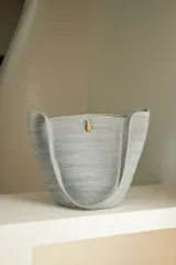 Bolso tipo tote confeccionado en soga de algodón color crudo, con asas de hombro y broche de bronce.