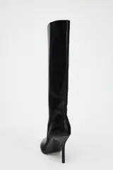 Bota negra de caña alta, confeccionada en cuero sintético, con terminación en punta y tacón fino.