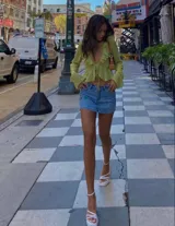 Blusa verde lima de manga larga con volantes y nudo frontal.