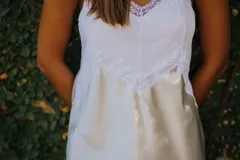 Camisón corto negro de satén con breteles finos y escote en V con puntilla blanca.