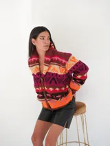 Saco de lana tejido con diseño jacquard en tonos topo, verde y rosado. Presenta cuello chal y botones frontales.