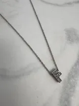 Collar de cadena fina plateada con dije de la letra "F" incrustada con strass.