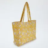 Bolso shopper acolchado amarillo con estampado floral en tonos beige.