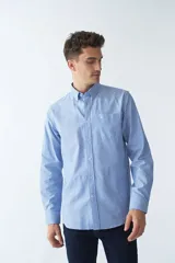 Camisa oxford celeste con rayas verticales blancas, de manga larga y corte regular. Tiene cuello abotonado, bolsillo en el pecho y logo bordado.