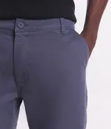 Pantalón de vestir marrón, de corte skinny, con bolsillos laterales y traseros. Se ajusta a la cintura con cinturón de cuero marrón.