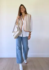 Bandolera color crudo con solapa de gamuza y cuerpo de cuero sintético texturizado. Tiene correa corta de cuero con tientos y forro de tela con bolsillo interno.