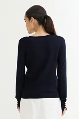 Cárdigan negro de tejido de punto fino con escote en V, cierre frontal con botones dorados y mangas largas con puños ajustados.