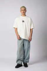 Remera color crema de corte oversize con la inscripción '90's' bordada en el frente y parche con imagen en la espalda.