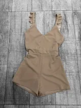 Mono corto color beige con escote en V, tirantes anchos con volados y corte a la cintura.