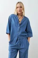 Camisa de jean celeste de corte recto, con cuello mao, mangas cortas y cierre frontal con botones.