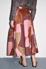 Falda midi de tiro alto confeccionada en hilatura de algodón con estampado geométrico multicolor. Detalle de pliegues en cintura y bajo evasé. Cierre con cremallera oculta en costura.